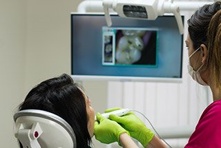 Dentist and patient looking at intraoral photos of teeth using advanced dental technology