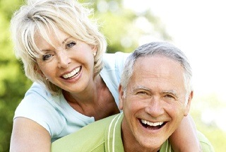 Smiling elderly couple with All on 4 dental implants in McKinney holding each other