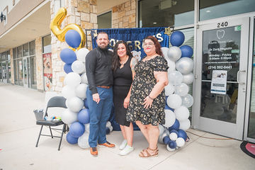 Man and two women standing outside dental office and smiling