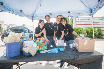 Four women standing behind table with gifts on it