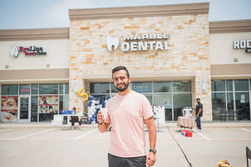 Man in light pink shirt standing in parking lot outside of dental office