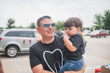 Man with sunglasses carrying his son