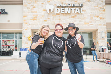 Three women wearing glasses smiling in parking lot