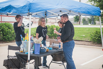 People eating and speaking at table under event umbrella