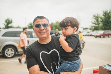 Smiling man with sunglasses carrying small child