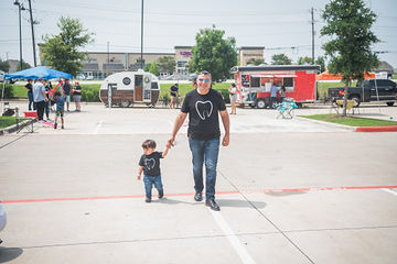 Man holding little boy's hand and walking through parking lot