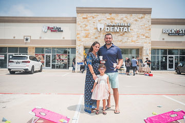 Parents with child smiling in parking lot