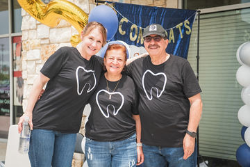 Two women and a man with black shirts with tooth icons