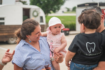 Woman carrying a little girl wearing a tiny hat