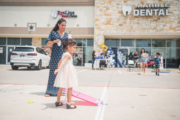Woman and little girl in dress walking through parking lot