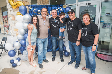 Multiple people in line in front of dental office smiling