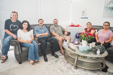 Five people sitting on couches near table with flowers