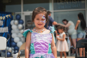 Close up of little girl with green and purple dress as well as butterfly face paint