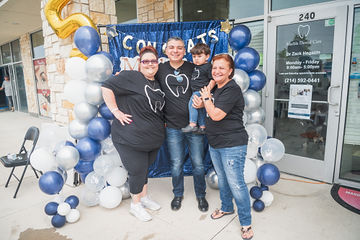 Three adults and little boy standing in front of celebratory sign