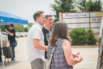 Two men and a woman standing together in a parking lot