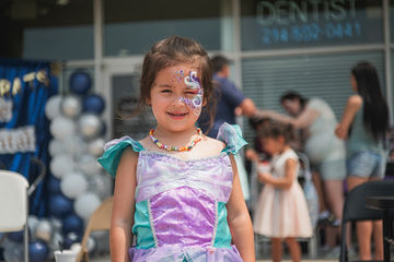 Happy little girl with multicolored dress and face paint