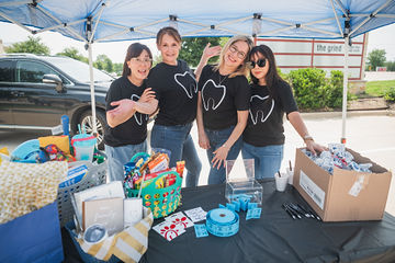 Four women standing and smiling under a tent together