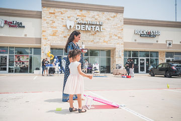 Little girl with mother playing beanbag toss in parking lot