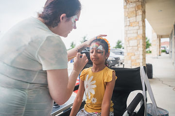 Woman putting face paint on little girl