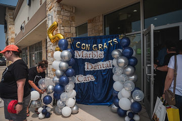 Message Congrats Marble Dental McKinney on blue curtain surrounded by balloons