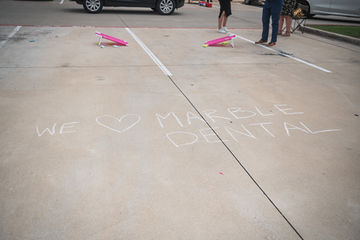 We Heart Marble Dental McKinney written on parking lot with chalk