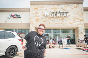 Woman with black shirt with tooth on it in front of Marble Dental McKinney