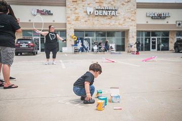 Little boy drawing on parking lot with chalk