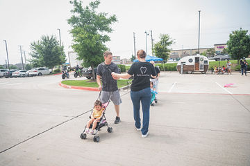 Man pushing stroller and greeting woman