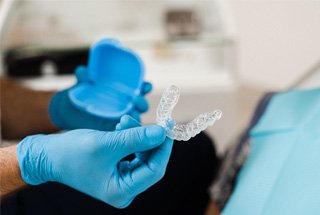 Dentist with blue gloves holding clear aligner
