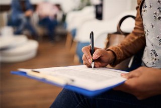 Closeup of patient filling out dental insurance forms in lobby