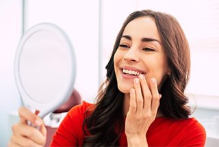 A patient smiling in McKinney while admiring her new dental crown