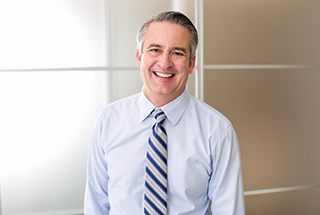 older man wearing blue striped tie smiling with dentures in McKinney