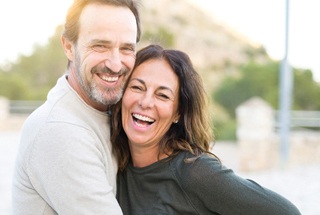 Man and woman hugging and smiling together while outdoors