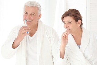 Older man and woman brushing teeth together