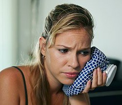 Pained woman suffering from a toothache with ice pack on face