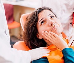 Pained woman visiting the dentist with hand on face