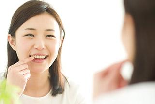 Woman poking her tooth while looking in the mirror