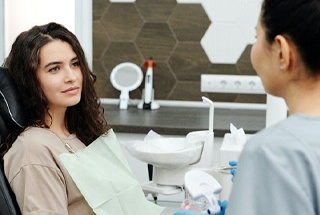 Woman in dental chair speaking to dentist