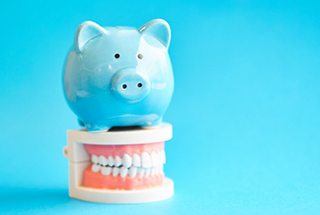 Piggy bank sitting on top a model of teeth 