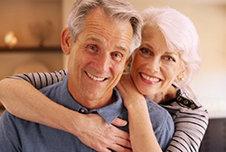 Older couple smiling with woman’s arms around man