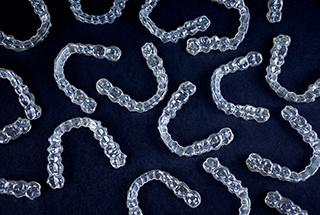 Bird’s eye view of many clear aligners on dark background