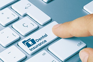 Closeup of a finger pushing ‘dental insurance’ button on computer keyboard