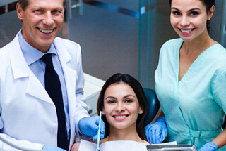 a female patient smiling alongside her dentist and hygienist