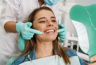 Dental patient using mirror to admire her new teeth