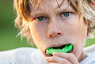 Teen boy placing sportsguard in his mouth