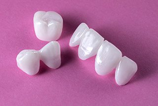 Dental crowns and dental bridges against pink background