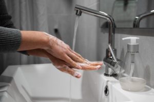 person washing their hands in their bathroom to protect themselves from COVID-19
