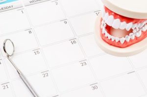 A dental mirror and dental diagram sitting on a calendar