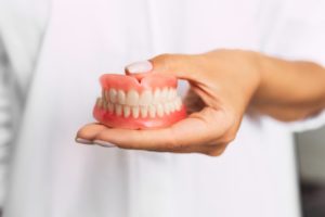 dentist holding a set of full dentures in McKinney 