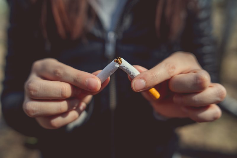 woman breaking cigarette in half